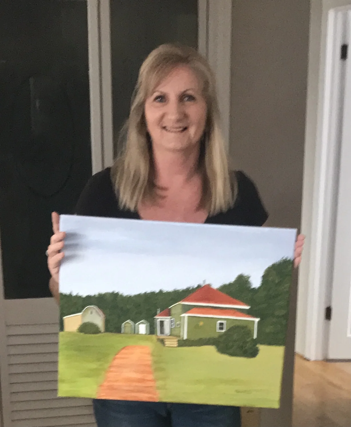 Tracey holding the finished painting of their home